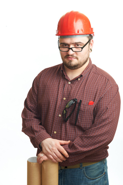 Serious builder in glasses and red hard hat with engineering drawing isolated on white - Fotó, kép