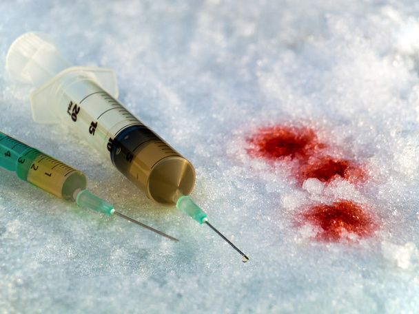 Deux injections de drogues avec du sang couché dans la neige et la glace
. - Photo, image