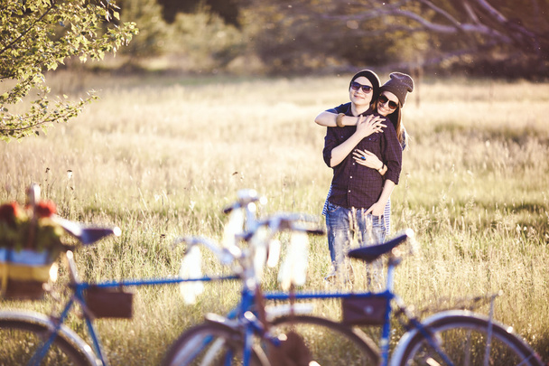 Two beautiful hipsters standing outdoor in summer with white vintage fixed gear bicycle - Foto, imagen