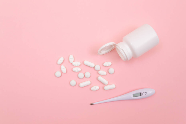 White Pills or Tablets with Electronic Thermometer on Pink Background - Foto, immagini
