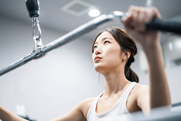 Азиатская девушка тренируется в тренажерном зале - Фото, изображение