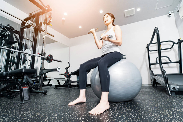 Asian young woman training with balance balls and dumbbells  - Photo, Image