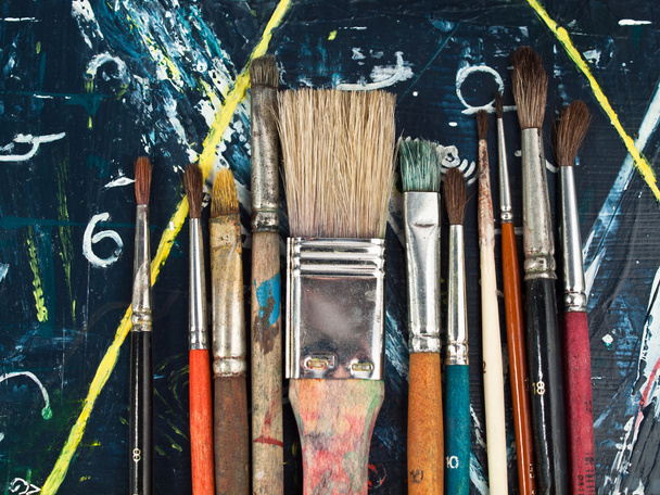 Paintbrushes lying on a blue-yellow paintig, art and craft equipment - Fotoğraf, Görsel