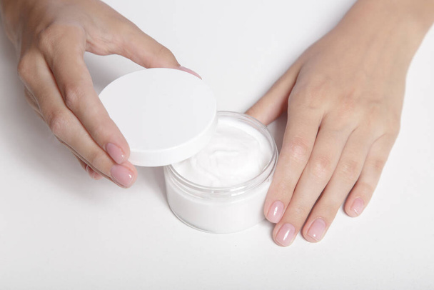 Woman's gentle hands with perfect manicure and a jar of cream - Photo, Image