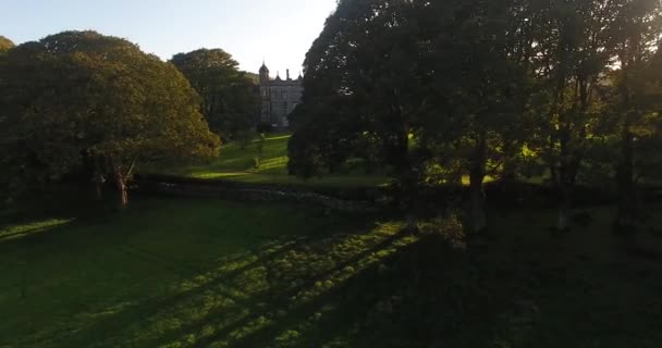 Aerial view of Glenarm Castle and sun throught trees in Ireland  - Metraje, vídeo