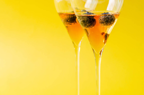 Dvě sklenky šumivého růžového vína s borůvkovým ovocem uvnitř posloužily jako uvítací nápoj. Koncept letních nápojů. - Fotografie, Obrázek