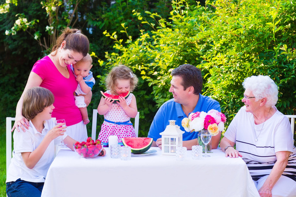 Familia comiendo fruta en el jardín
 - Foto, imagen