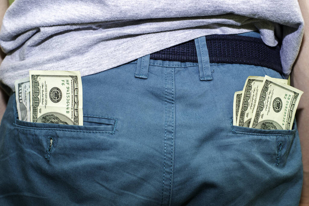 Kaksi sadan dollarin seteliä denim-housujen taskussa. Laadukas kuva - Valokuva, kuva