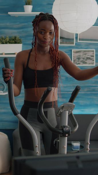 Black woman athletic training on elliptical bike practicing cardio sport - Foto, Imagem