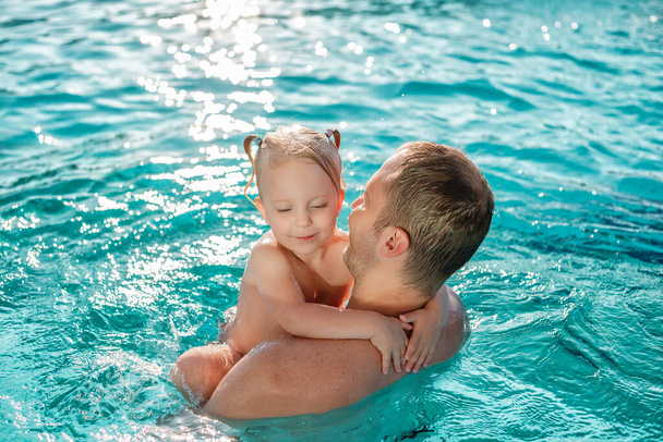 Apa a kislányával szórakozik a nyári vakáción fröccsenő szabadtéri úszómedencében  - Fotó, kép