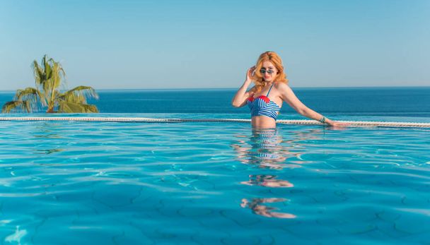 Tropik tatil köyünde güzel bir rahatlama, tatil konsepti, havuzda güneşlenen güzel bir kadın. - Fotoğraf, Görsel