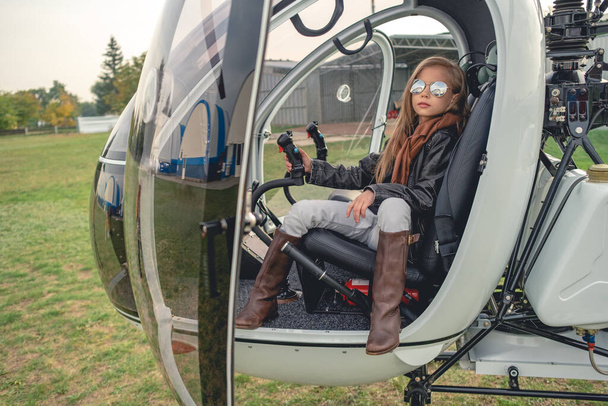 Confiante tween menina em óculos de sol espelhados sentado em helicóptero - Foto, Imagem