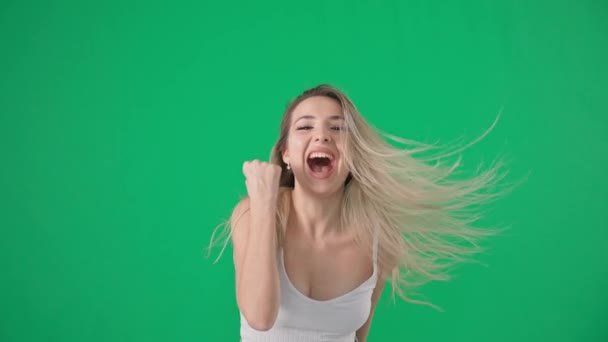 luck and success, emotional happy young woman rejoices in victory shows with hands yes jumps and turns her head on a green screen, chrome key - 映像、動画