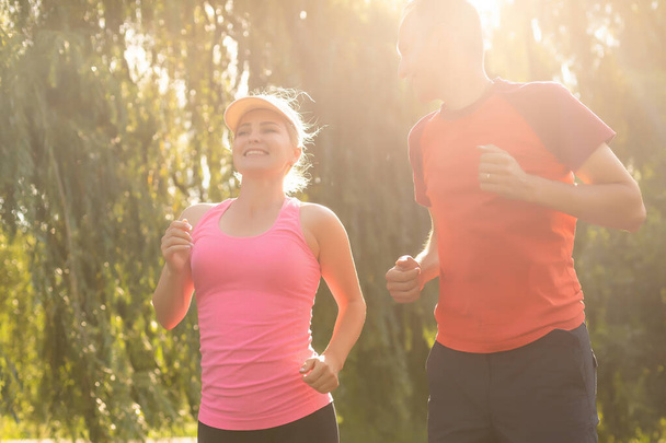 młoda para ciesząca się zdrowym trybem życia podczas joggingu wzdłuż wiejskiej drogi, ćwiczeń i koncepcji fitness - Zdjęcie, obraz