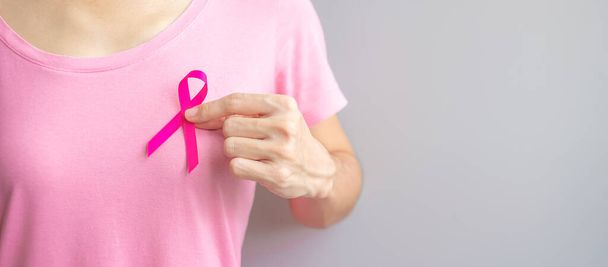 Октябрь месяц осведомленности о раке молочной железы, пожилая женщина в розовой футболке с рукой, держащей розовую ленту для поддержки людей, живущих и больных. Концепция Международного дня женщин, матерей и борьбы с раком - Фото, изображение