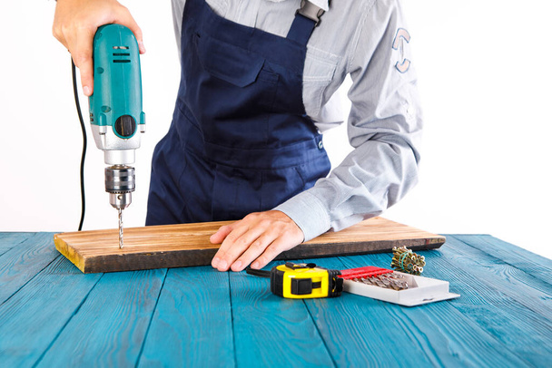 Handyman in blue uniform works with electricity automatic screwdriver. House renovation conception. - Фото, зображення