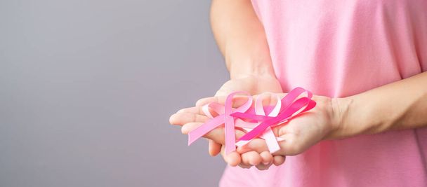 Październikowy miesiąc świadomości raka piersi, starsza kobieta w różowej koszulce z ręką trzymającą różową wstążkę za wspieranie ludzi żyjących i chorych. Międzynarodowy Dzień Kobiet, Matki i Światowego Dnia Raka - Zdjęcie, obraz