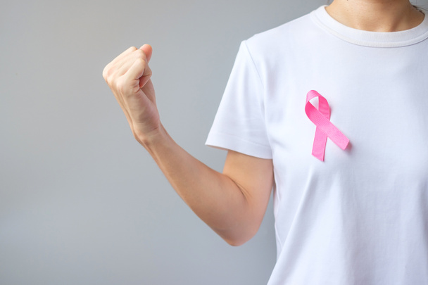 October Breast Cancer Awareness month, elderly Woman in white T- shirt with Pink Ribbon and fist sign for supporting people living and illness. International Women, Mother and World cancer day concept - 写真・画像