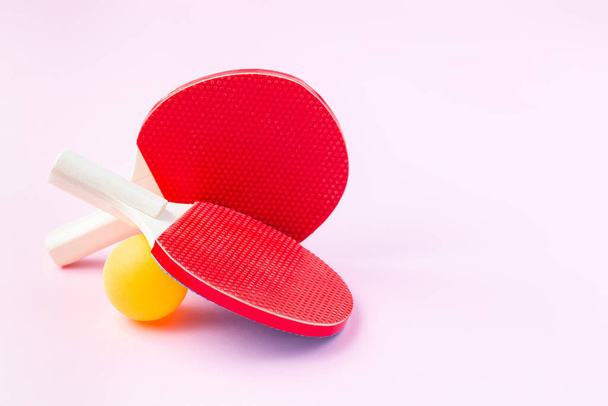 Children mini rackets ping pong or table tennis and orange ball a on pink background, horizontal, copy space. Healthy lifestyle concept - Fotoğraf, Görsel