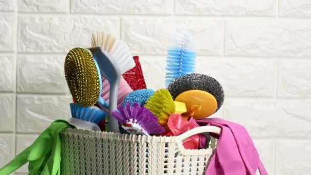 plastic basket with brushes, disinfectant in a bottle, rubber gloves on the background of a white brick wall. House cleaning items set - Footage, Video