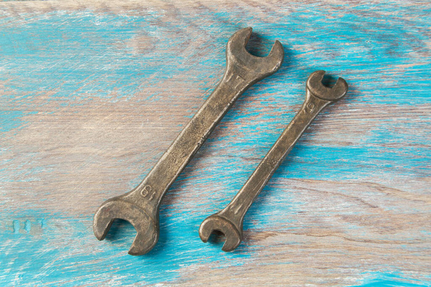 Комплект из двух винтажных бронзовых гаечных ключей на потрепанном голубом деревянном фоне. Копирование текста. - Фото, изображение