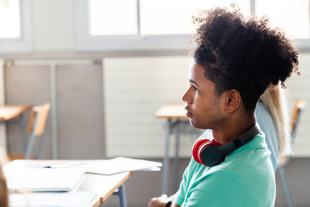 Αφροαμερικάνος έφηβος στην τάξη. Άντρας μαθητής λυκείου ακούει τον δάσκαλό του. Αντιγραφή χώρου. Εκπαιδευτική έννοια. - Φωτογραφία, εικόνα