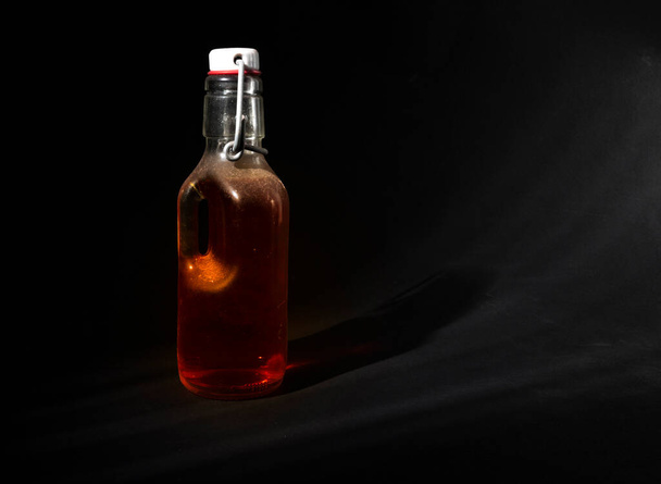 Стеклянная бутылка закрыта металлической крышкой с янтарной жидкостью внутри - Фото, изображение