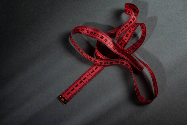 Красная сантиметровая лента, случайно брошенная на сером фоне - Фото, изображение