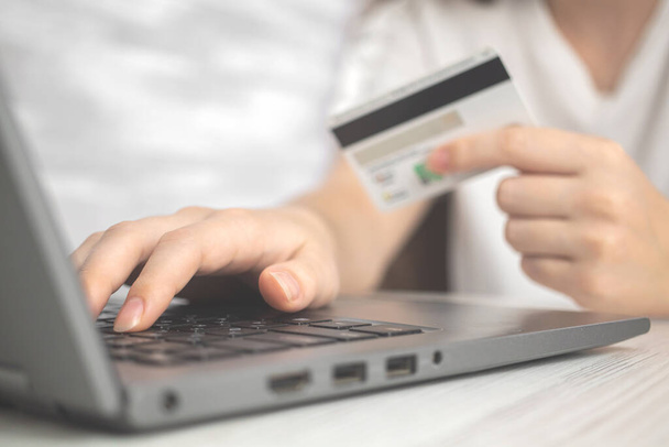 Kobieta korzystająca z laptopa z kartą kredytową w dłoni. Koncepcja zakupów internetowych, wydawania pieniędzy i handlu elektronicznego. Kontekst bankowości internetowej  - Zdjęcie, obraz