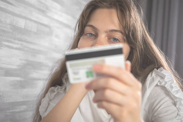 Frau schaut auf Kreditkarte, Shopaholic und Taschengeldkonzept. Kreditkarte in der Hand und junge Frau wartete auf das Geld für Online-Einkäufe - Foto, Bild