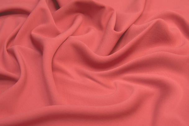 Tela satinada brillante atlas de seda roja con pliegues, ondas de tela. Fondo rojo de tela rosa. De cerca. - Foto, Imagen