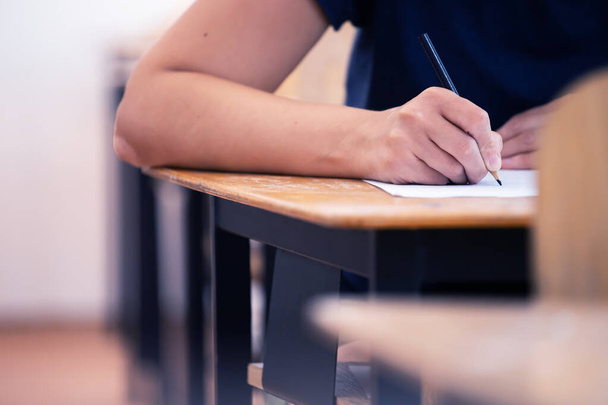 High school or university student holding pencil writing on paper answer sheet. Final exam concept. - Φωτογραφία, εικόνα