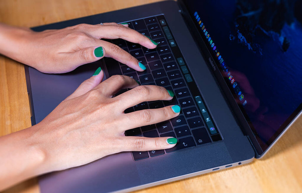 Cyberjaya, Malaysia - October 13, 2020:  Woman hands typing on a computer keyboard. Female hands writing on a laptop keyboard. Fingernails are painted in green. Home office during the lockdown - Fotoğraf, Görsel