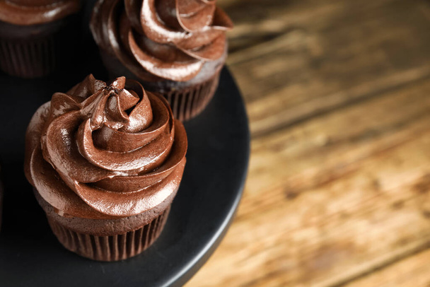 Dessert stand with delicious chocolate cupcakes on wooden table, closeup. Space for text - 写真・画像