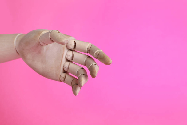 Wooden mannequin hand on pink background. Space for text - Photo, image