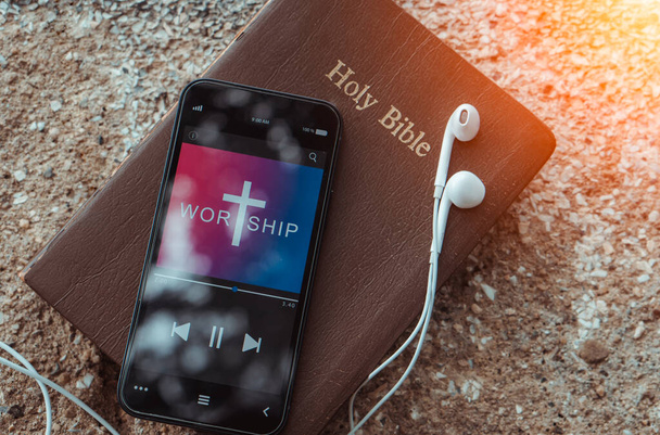 Biblia con teléfono y auriculares, Concepto escuchar canción de adoración. - Foto, imagen