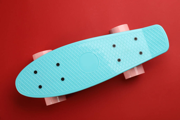 Turquoise skateboard on red background, top view - Фото, изображение