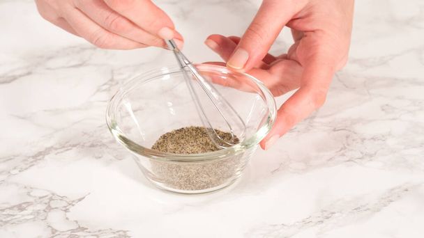 Step by step. Mixing salt and pepper in a small glass bowl with blending whisk. - Photo, image