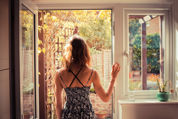 Woman standing in doorway at sunrise - Foto, imagen
