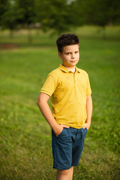 pretty little boy with dark hair holding his hands in the pockets and smiling - Fotoğraf, Görsel