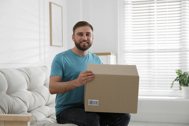 Happy young man with parcel at home - Photo, image