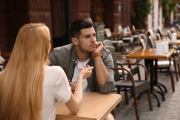 Man getting bored during first date with overtalkative young woman at outdoor cafe - Fotografie, Obrázek