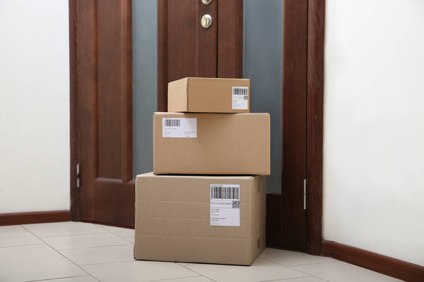 Stacked parcels near door on floor. Delivery service - Fotografie, Obrázek