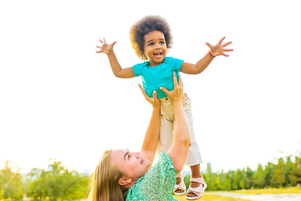 маленькая девочка с крутыми афро кудрявыми волосами веселится вместе с мамой outdor - Фото, изображение
