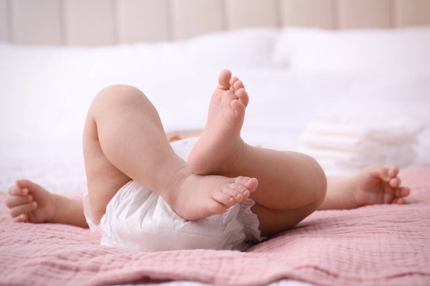 Little baby in diaper on bed, closeup - Foto, imagen