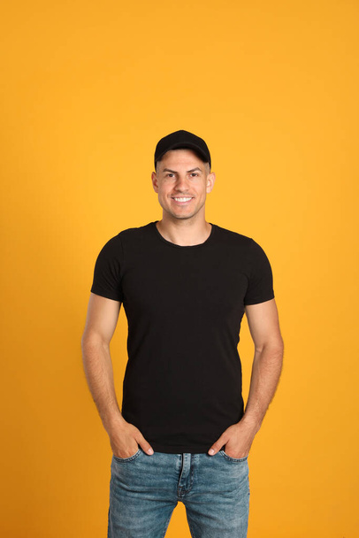 Happy man in black cap and tshirt on yellow background. Mockup for design - Foto, Imagen