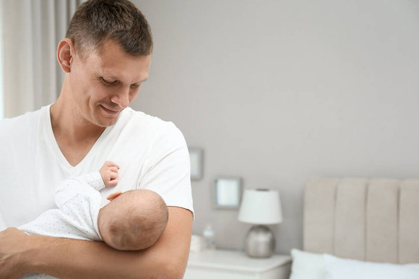 Happy father holding his cute baby at home, space for text - Fotoğraf, Görsel