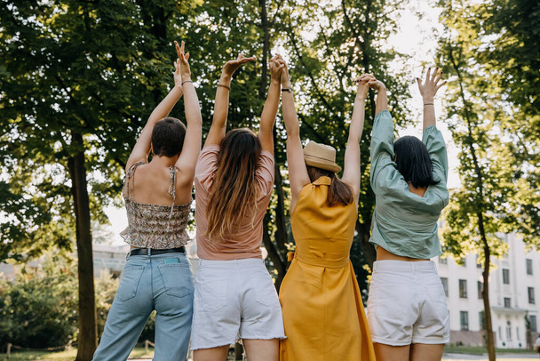 Gruppe von vier Frauen im Freien, Spaß haben, Händchen halten in der Luft. - Foto, Bild