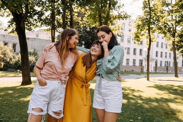 Group of three young women in a park, having good time, hugging and laughing. - Foto, afbeelding