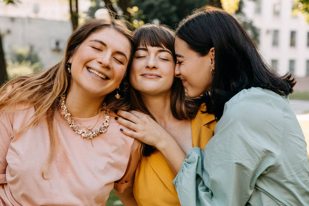 Nahaufnahme Porträts von drei jungen Frauen, die sich umarmen und lächeln. - Foto, Bild